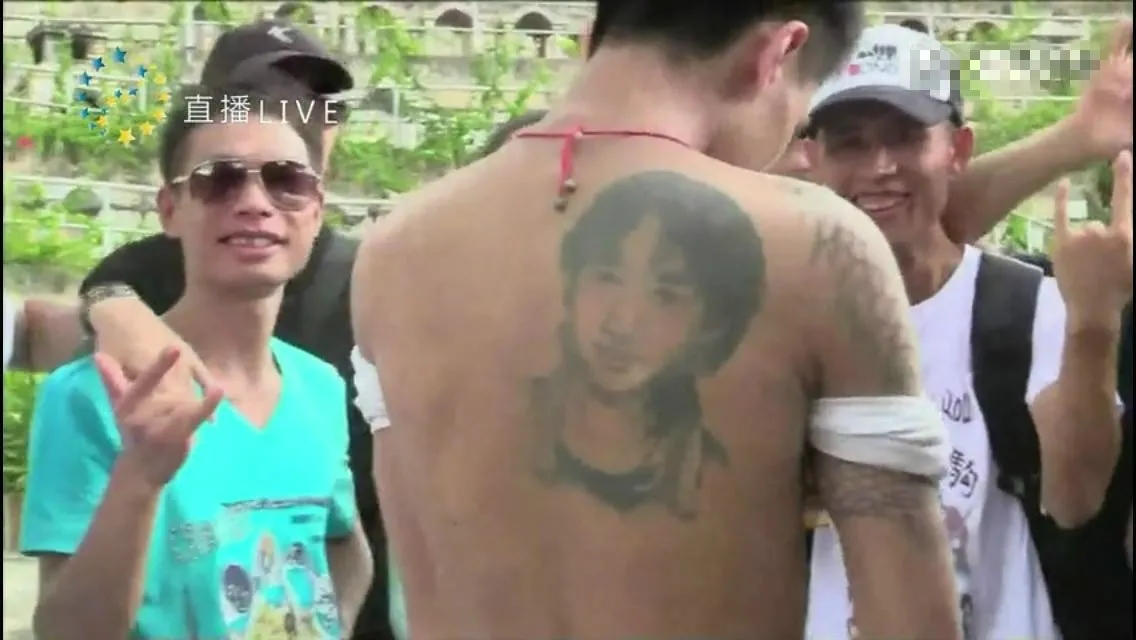 畫面中有人赤裸上身，展示家駒的肖像紋身，另有兩名男子笑容滿臉入鏡。（網上截圖）