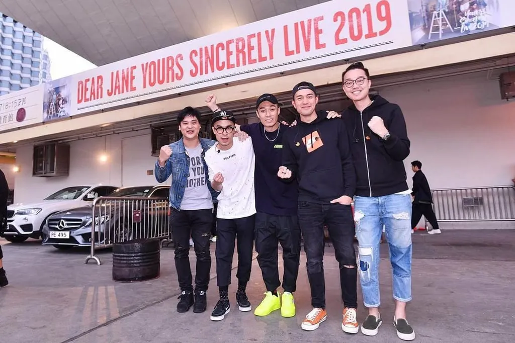 Dear Jane posing in front of an ad for its concert, “Yours Sincerely Live” in 2019. Photo: @dearjaneofficial/Instagram