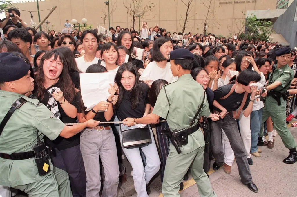 Police officers block emotional mourners as a hearse carrying the coffin of Wong Ka-kui passes in July 1993.