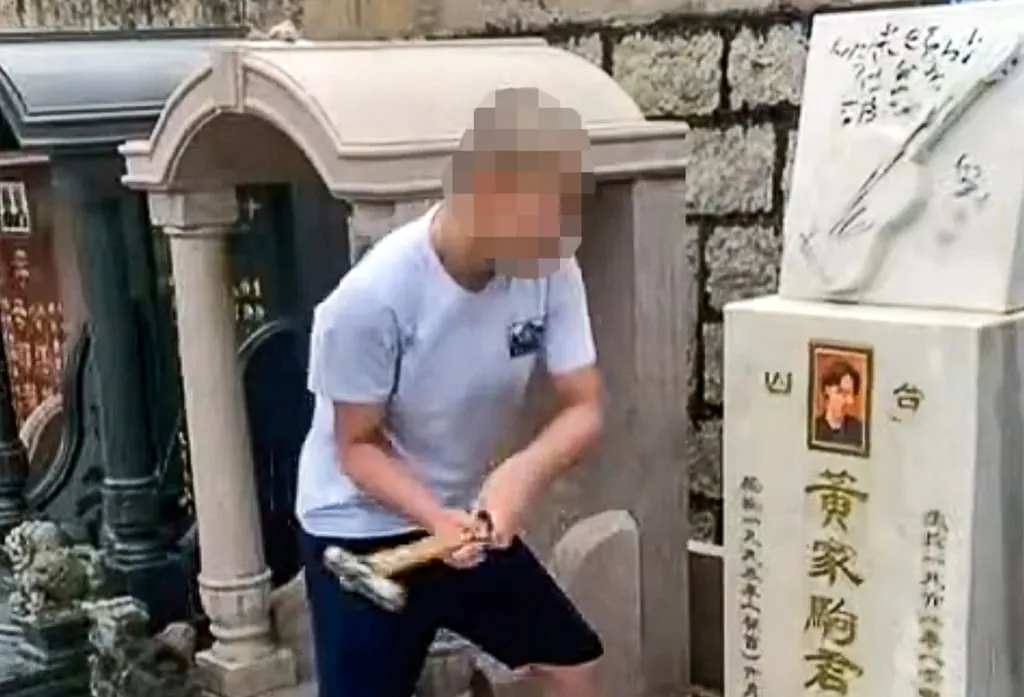 A screenshot from a clip showing a man attacking the ceremonial plaque of Beyond’s lead singer with a hammer. Photo: Facebook/Booska Kevin